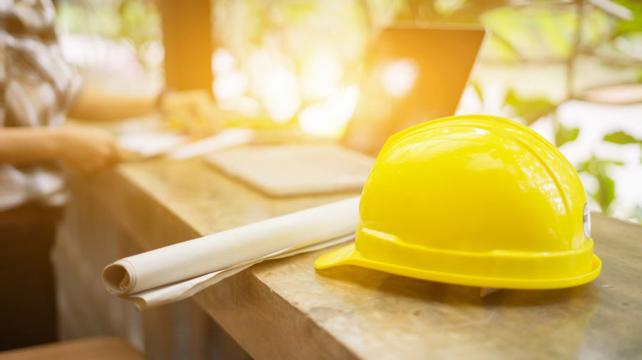 yellow hard safety helmet hat for safety project of workman as engineer  on work place, architect man working with laptop on background,construction project ,Business concept